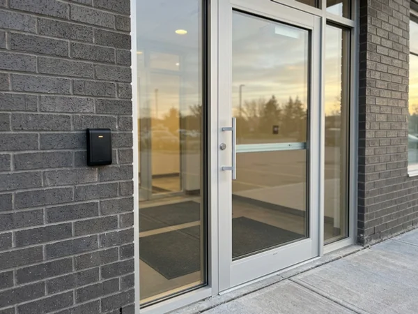 Card reader beside a new clear anodized lobby door with exit device